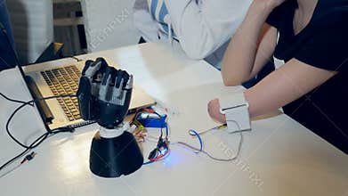 Young woman testing robotic bionic arm. Futuristic cybernetic technology in real life.