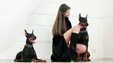 Longhaired model wearing long black fur coat and high heels boots touching doberman and walking away