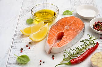 Fresh raw salmon steak with lemon, olive oil and spices on rustic wooden background.