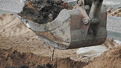 Excavator bucket digging soil sand and dirt hole at building site. Slowmotion