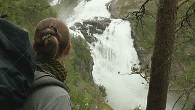 Girls look at waterfall in mountains