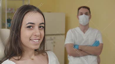 Dental office. Happy female patient looking at the camera. in the background a dentist. The concept of advertising