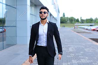 Arabic guy in business center stands smiling walking slow