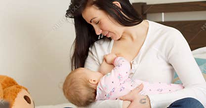 Mother breast feeding her baby on bed