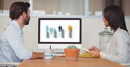 Side view of business people looking at graph on computer screen while sitting in office