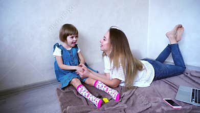 Loving girl and mother communicate with little daughter and happily spend time together in room in daytime.