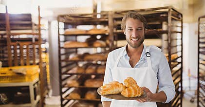 Happy small business owner man holding croissants