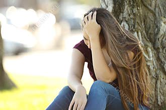 Sad woman lamenting sitting in a park