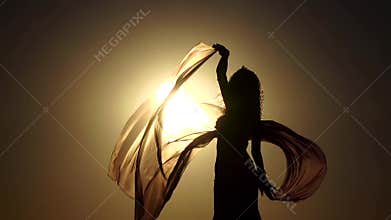 Girl on the seashore gracefully dances her body against the sunset. Silhouette. Slow motion