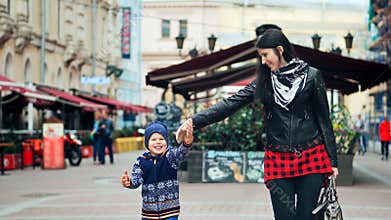 Happy mother and her little son walking and laughing in the city