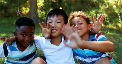 Portrait of happy kids waving hands in park