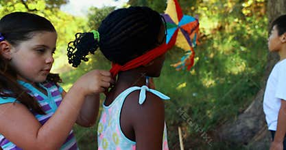 Girl tying blindfold on her friends eyes in park