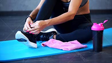 Close up shot of the women`s feet, who ties up the shoelaces on the sneakers