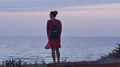 Young woman walking on seashore at dusk