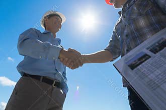 Builders Handshake, Architect And Contractor Agreement During Meeting Discussing Blueprint Buiding Plan On Construction
