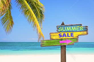 Summer sale written on pastel colored wooden direction signs, beach and palm tree background