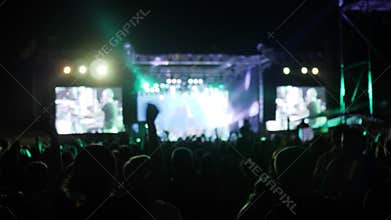 Crowd jump and dance at rock festival, arms raised of fans in bright lights of stage, excited audience waving hands