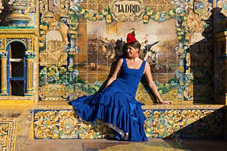 The woman with blue flamenco dress sitting in Plaza de Espana
