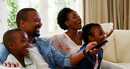 Parents and kids having fun while watching television in living room
