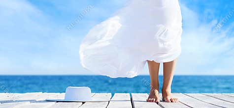 Beautiful and healthy feet of a young girl in white dress on a w