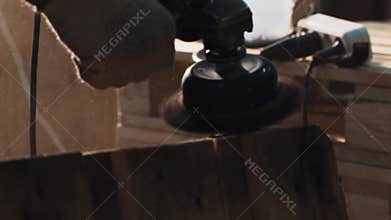 Worker hand in glove use grinder machine to smooth wooden pallet edges