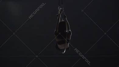 Beautiful gymnast make an element `man in the moon` on aerial hoop