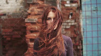 Closeup portrait of a redheaded girl with a mysterious look. girl with freckles looks at camera. hair flying in the wind