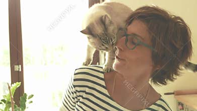 Domestic cat playing on the shoulder of smiling beautiful woman. Indoors setting. Toned image, vintage style, retro filter, backli