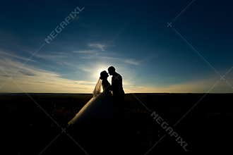 wedding couple with the sunset. Silhouette of Bride and Groom kissing on the romantic wedding