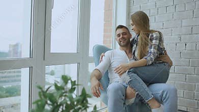 Beautiful young couple relax sitting on chair and enjoying view from balcony of new loft apartment