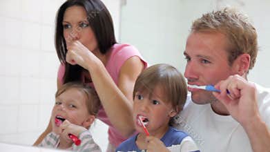 Family Reflected In Bathroom Mirror Brushing Teeth