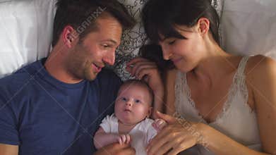 Overhead View Of Parents Lying In Bed Cuddling Baby