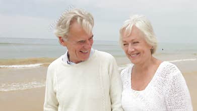 Senior Couple Walking Along Misty Beach