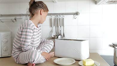 Young Girl Wearing Pajamas Putting Bread Into Toaster