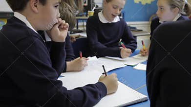 Pupils Working At Table With Teacher Helping Them