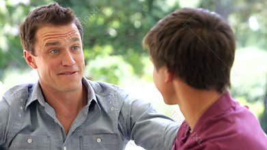 Father And Teenage Son Talking On Sofa Together