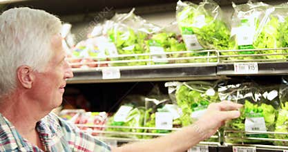 Senior man picking out salad in supermarket