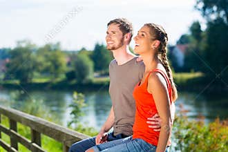 Couple sitting at riverbank in summer