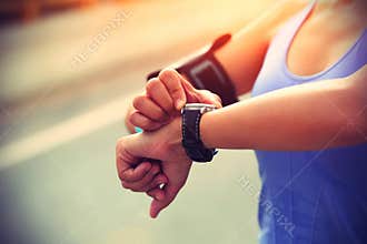 Young woman jogger ready to run set and looking at sports smart watch