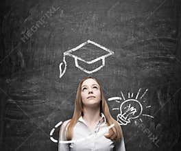 Beautiful lady is thinking about education. A graduation hat and a light bulb are drawn on the chalkboard above the lady.