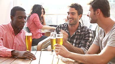 Three Male Friends Enjoying Drink At Outdoor Rooftop Bar
