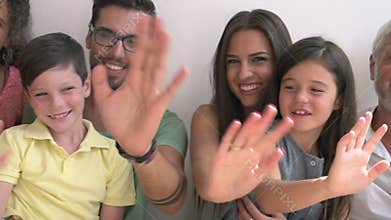 Multi Generation Family Standing Against Wall And Waving