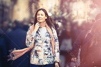 Beautiful woman with scarf walking in the crowd city. Winter season