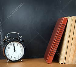 Back to school background with chalkboard, books and alarm clock