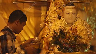 Buddhist devotees bathing Buddha statue for blessings at Shwedagon