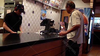 People ordering food and paying cash at KFC check out counter