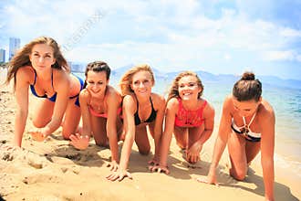 Closeup cheerleaders in bikinis crawl in line along wet sand