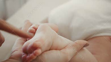 Baby Feet in Mother Hands. Tiny Newborn Baby's Feet on Female Heart Shaped Hands Closeup. Mom and her Child. Happy