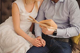 Close up Sweet Young Couple Sitting at Couch In the Living Room, Reading a Book Together