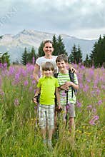 A woman and two boys stand on field of fireweed